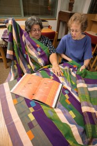 Curator at the National Museum of African Art, Bryna Freyer, and Warren M. Robbins Librarian, Janet Stanley, examine a sample of African textile art in the Robbins Library.