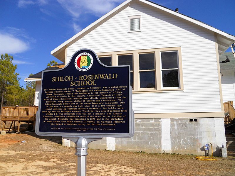 Exterior of Rosenwald School in Notasulga, Alabama. White building with historic marker in front.