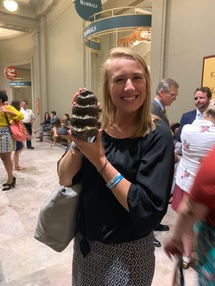 Young woman holding large fossilized megalodon tooth.