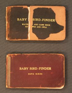 Two copies of "Baby Bird Finder" books, one with torn brown leather cover, the other with red leather cover