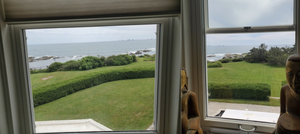 View of windows looking out over manicured lawn with ocean in background. 